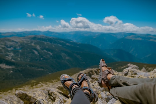 two person's feet cross leg on gray rocks in Retezat National Park Romania