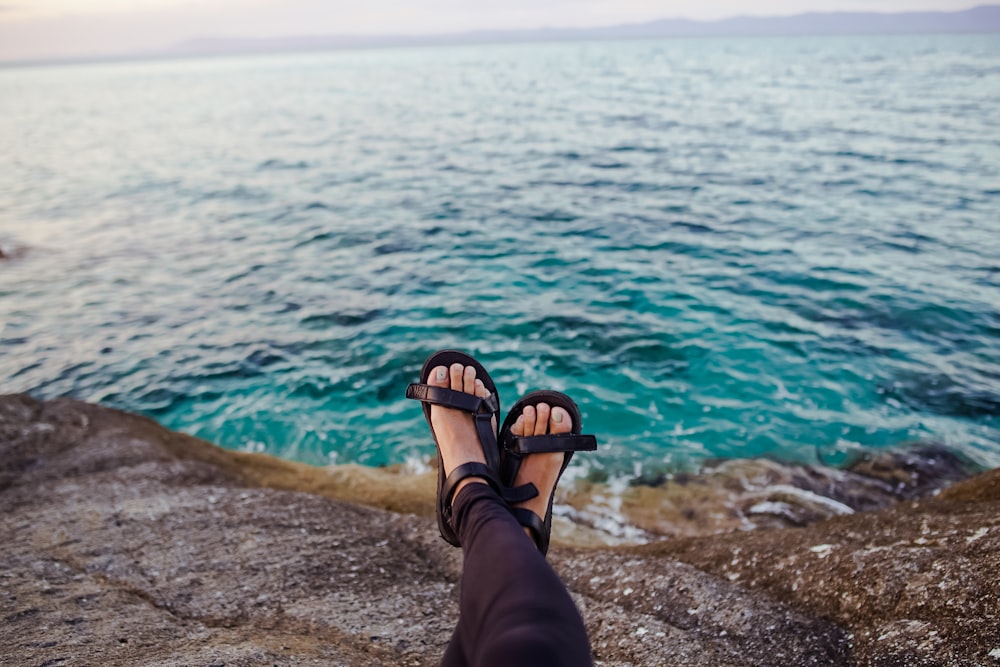 person cross leg next to body of water