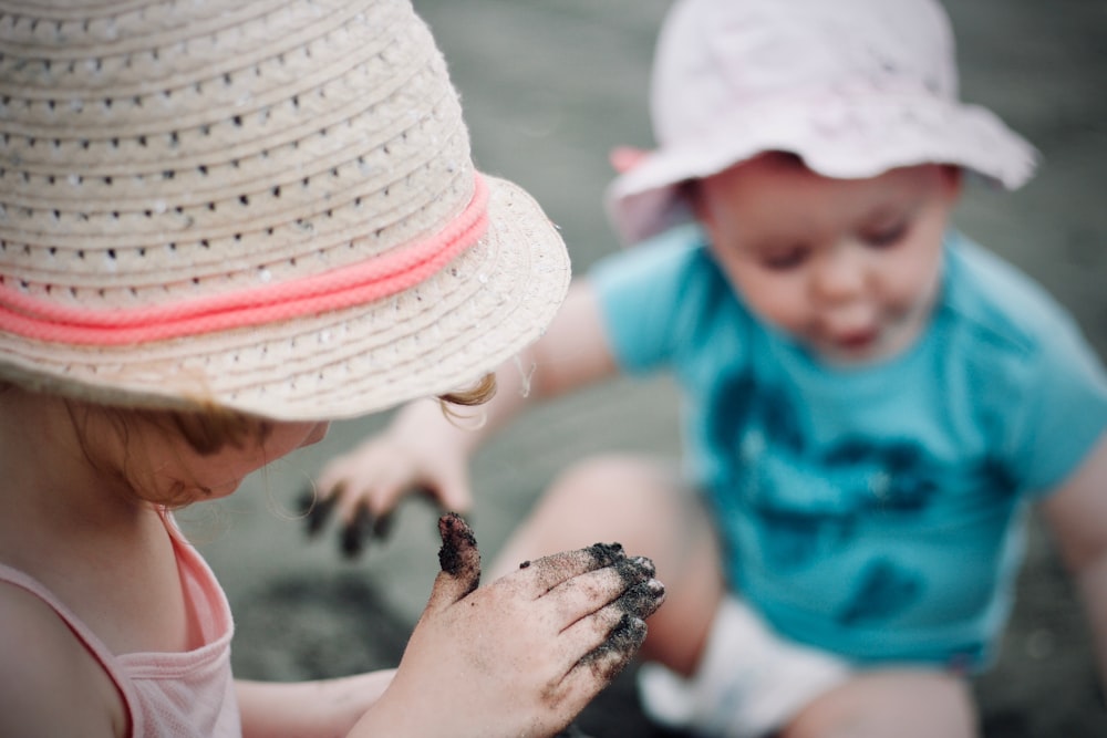 砂を保持している日よけ帽子をかぶった女の子のクローズアップ写真