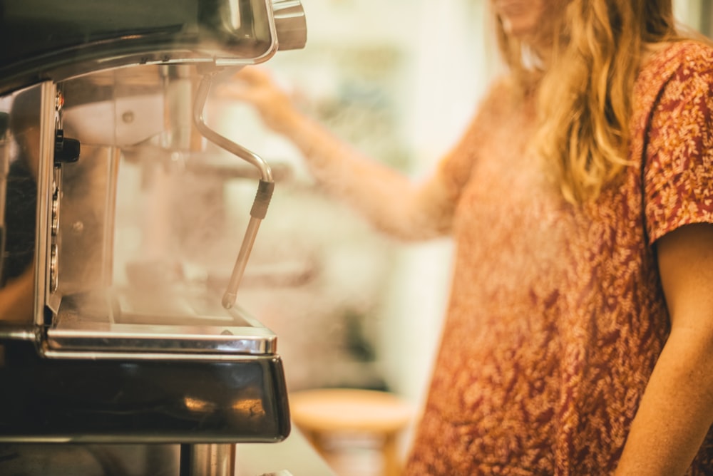 person in front of gray commerial espresso machine