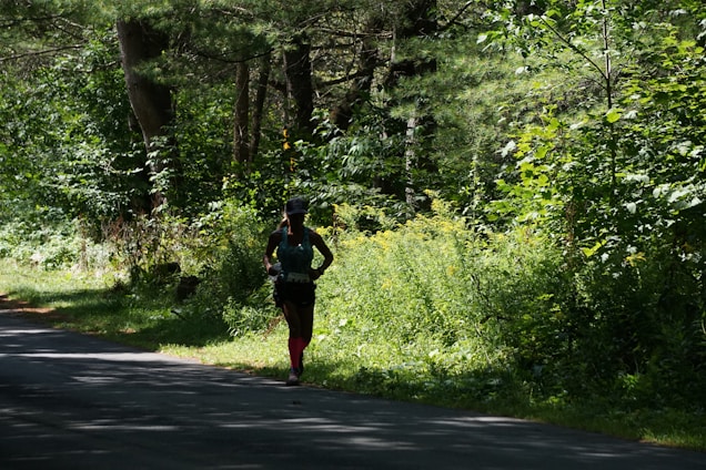 A runner sprinting at dawn wearing bright, lightweight neon shorts on a forest trail.