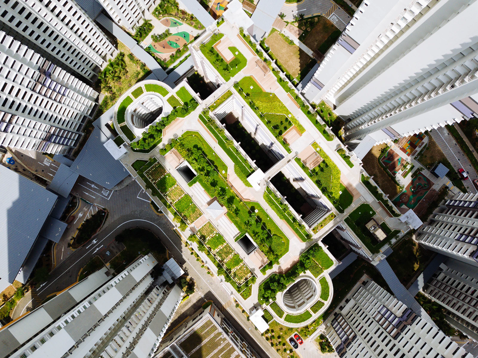 Aerial view of a green, sunlit building complex with a rooftop terrace