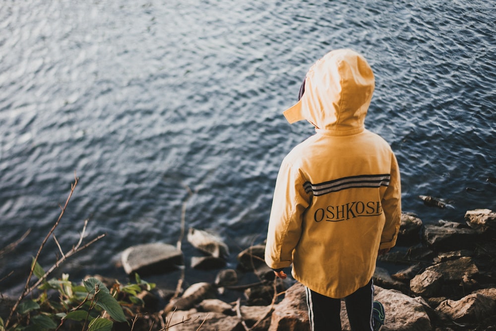 person in yellow jacket standing on cliff