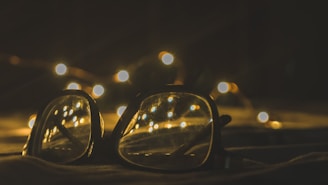 Close-up of a customer happily trying on glasses with a warm golden light in the background.