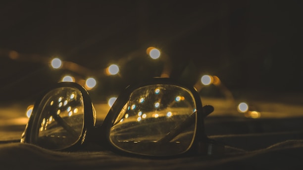 Close-up of a customer happily trying on glasses with a warm golden light in the background.