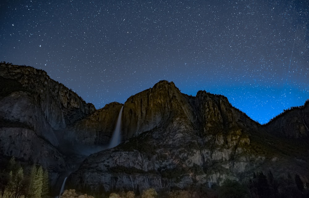 Wasserfälle auf braunem, zerklüftetem Berg unter blauem Himmel in der Nacht