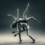 A woman flipping over a man, back to back.