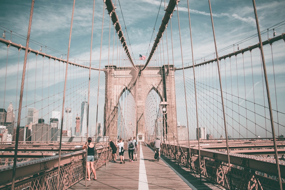 personas caminando por el puente de Brooklyn durante el día