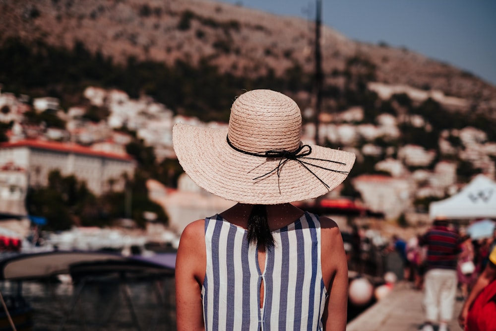 woman wearing gray and white striped sleeveless top and brown sun hat at daytime