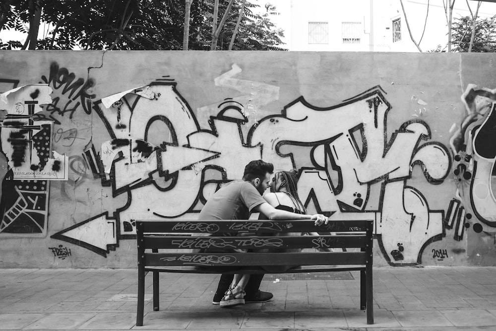 grayscale photo of man and woman sitting on bench