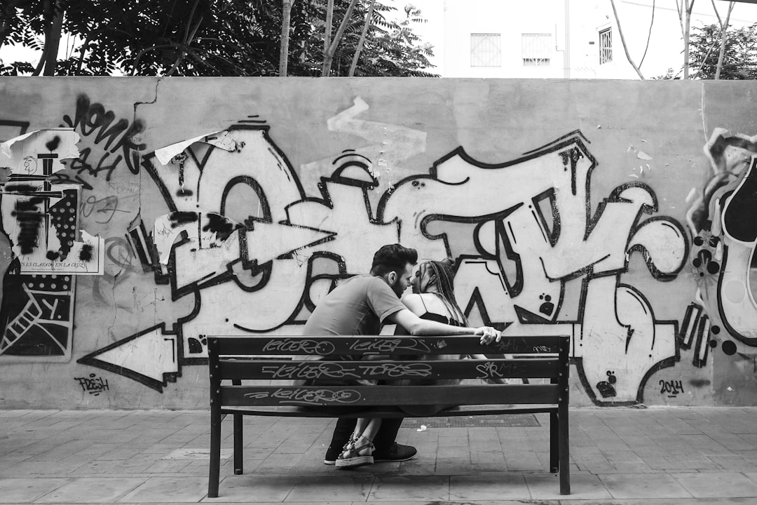 grayscale photo of man and woman sitting on bench