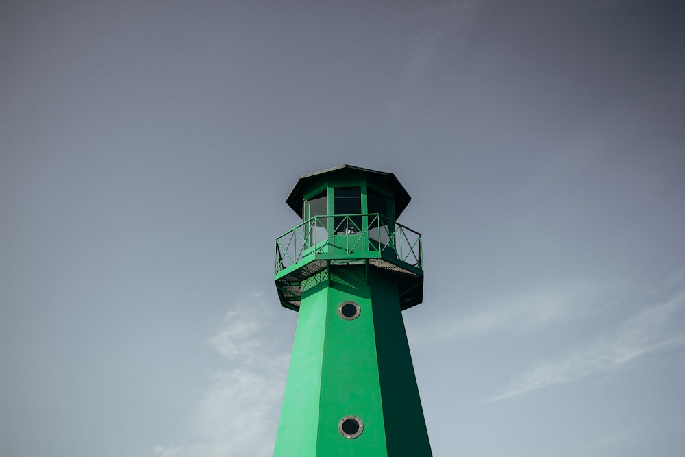 Grüner Leuchtturm tagsüber unter bewölktem Himmel