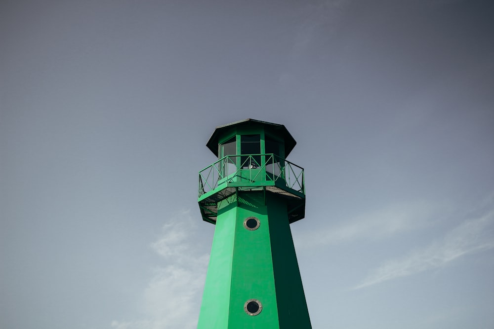 green lighthouse under cloudy sky during daytime