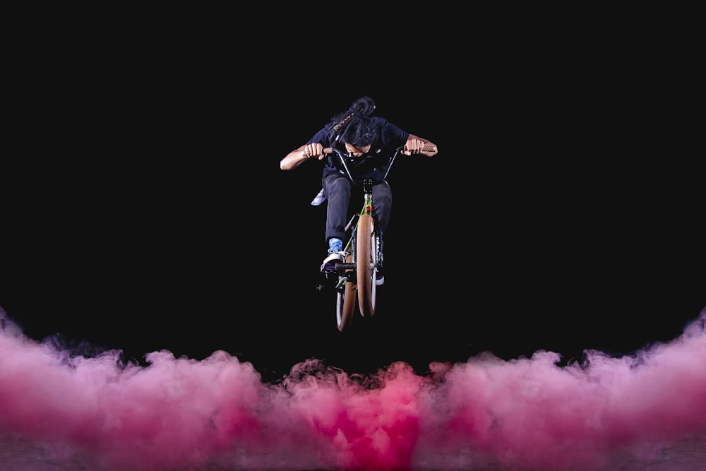 hombre montando bicicleta BMX realizando acrobacias con nieblas rojas