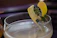 A close-up of a golden-hued signature cocktail with a delicate garnish on a sleek black bar counter.