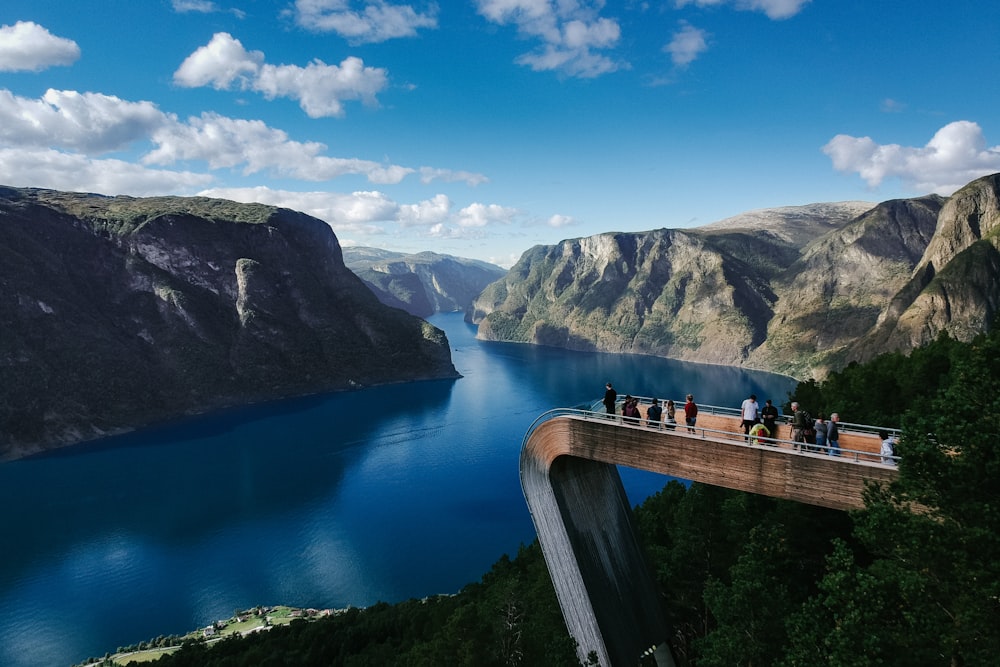 Menschen, die auf einer Brücke stehen und durch einen Berg blicken, der von Wasser umgeben ist