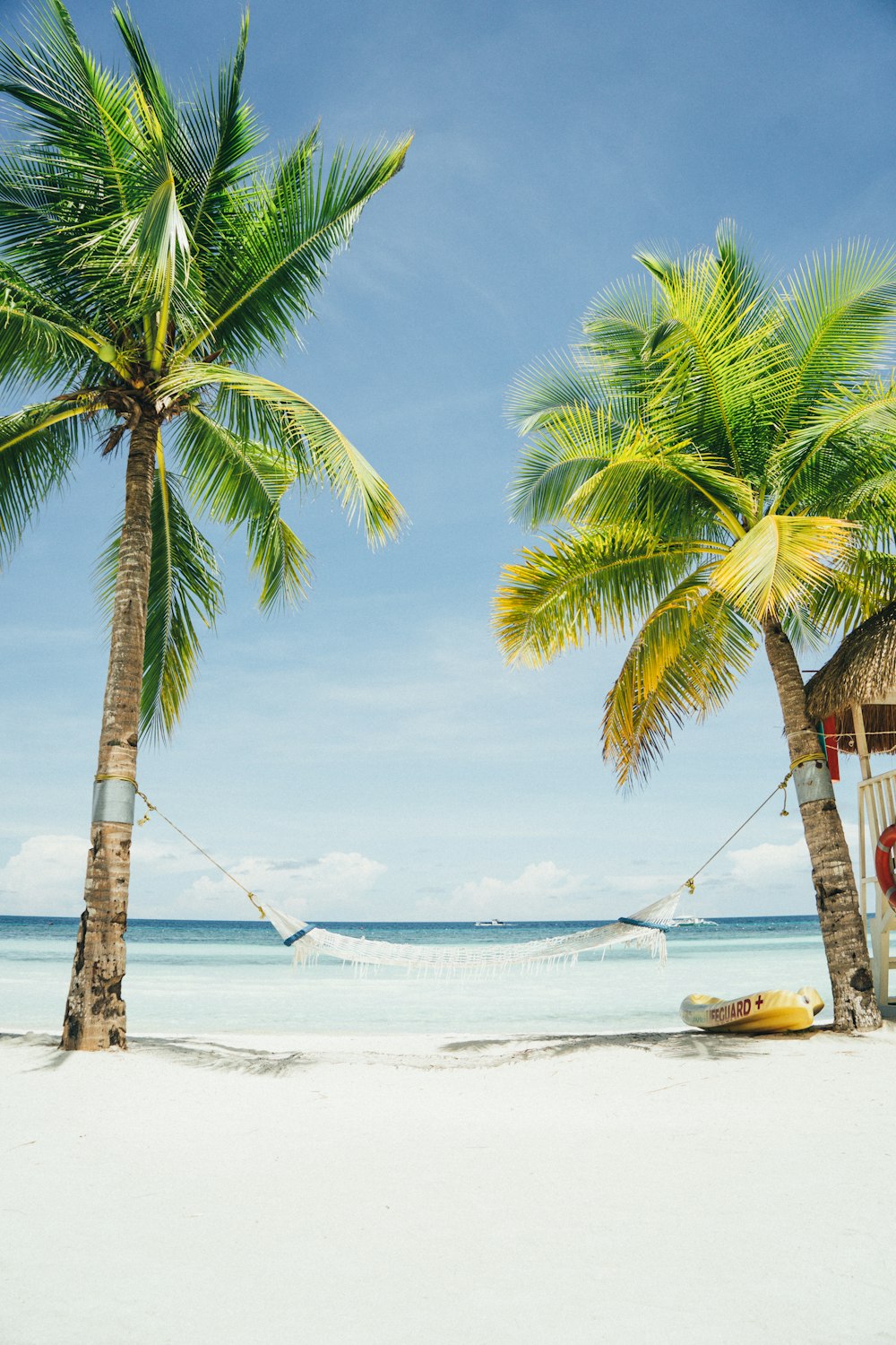 Two tall trees connecting a hammock on a tropical beachfront.