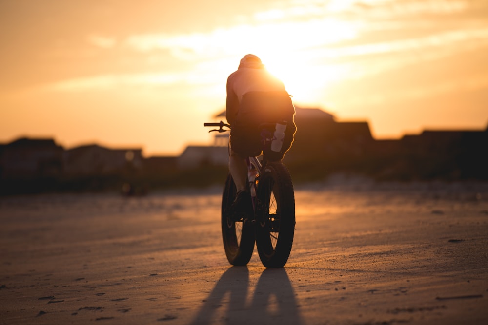 personne faisant du vélo sur un vélo à gros pneus au coucher du soleil