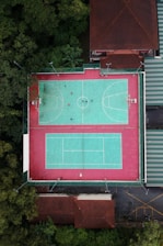 A multi-sport court with basketball hoops and volleyball nets set up for a game