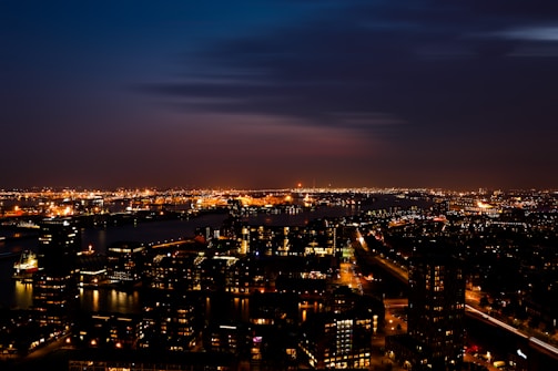 Nighttime panorama of Madrid's skyline with illuminated buildings and the river reflecting lights.