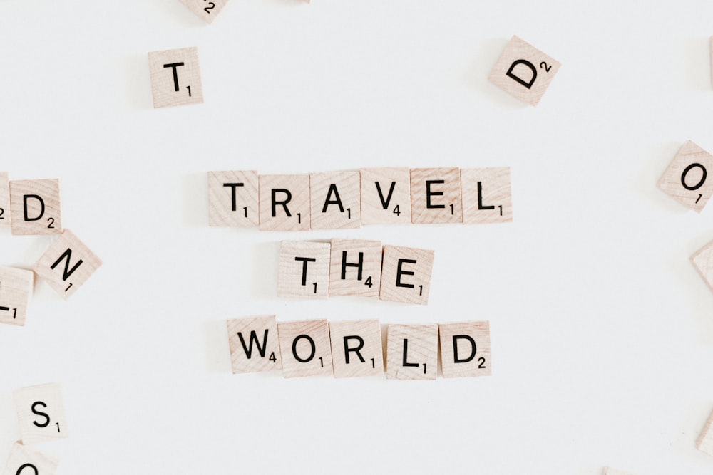 Scrabble letter pieces that spell "Travel the world."
