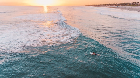 person riding on knee board on body of water in Huntington Beach United States