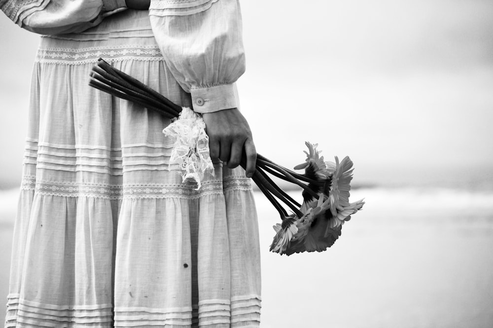 person in dress holding bouquet of petaled flowers