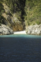 A small secluded beach on a Greek island with turquoise waters and rocky cliffs.