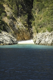 A small secluded beach on a Greek island with turquoise waters and rocky cliffs.