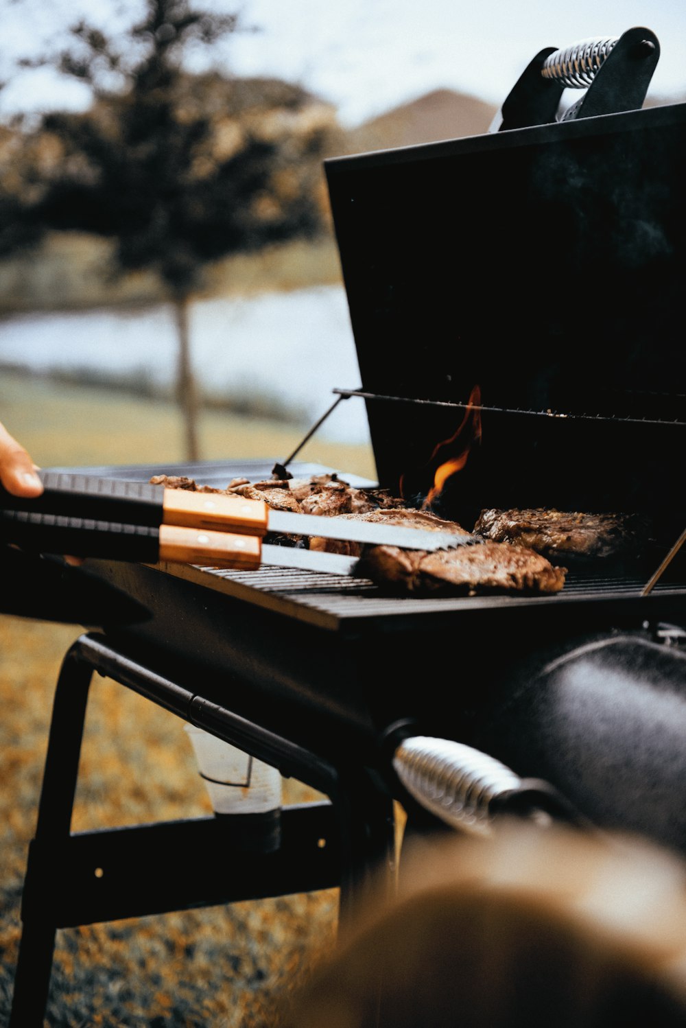 person grilling meat outdoors