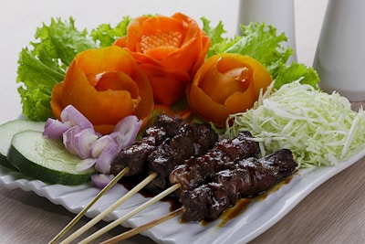 A vibrant plate of grilled satay skewers garnished with fresh vegetables.