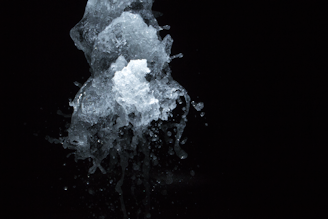 A dynamic splash of water captured in mid-air against a dark background, showcasing intricate and transparent textures with droplets scattering in various directions.