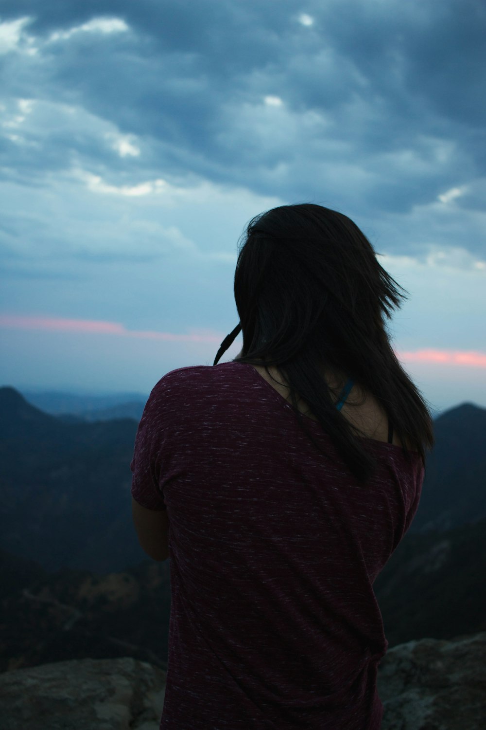 woman in maroon shirt standing on top of mountain during daytime