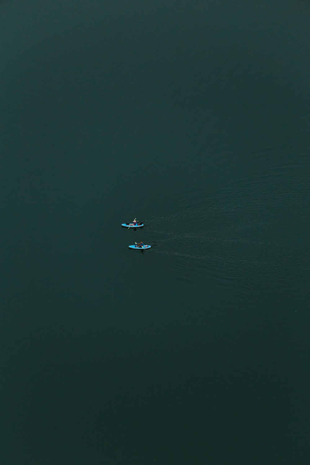two people kayaking at calm body of water
