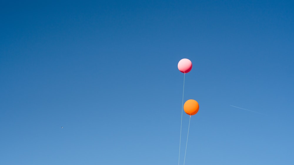 zwei orangefarbene und rosa Luftballons