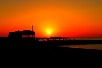 A vibrant vintage poster featuring a sunset over Sarasota beach with warm orange and pink hues.