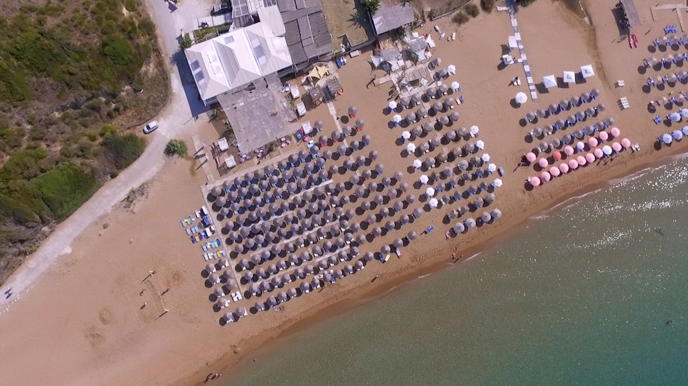 Foto aérea de paraguas cerca de un cuerpo de agua tranquilo durante el día