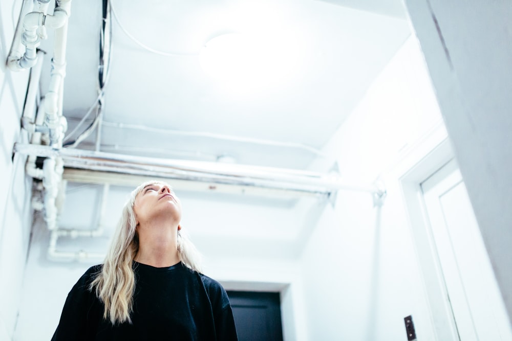 woman in black crew-neck shirt looking up the ceiling