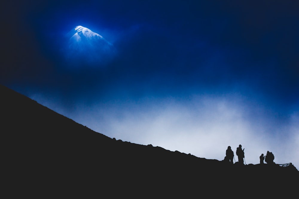 four person standing on cliff silhouette
