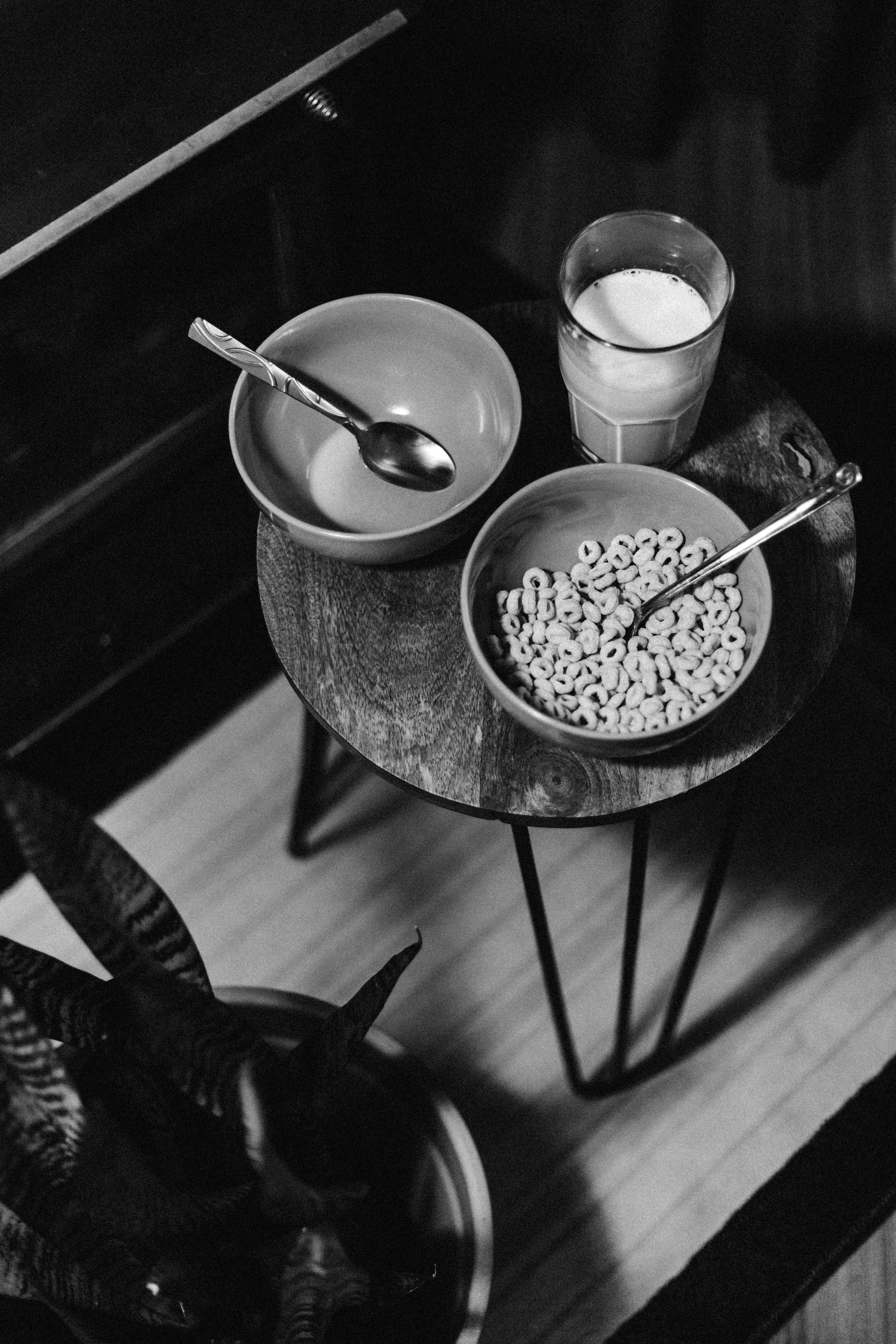 grayscale photo of bowl of cereal beside glass of milk
