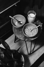 grayscale photo of bowl of cereal beside glass of milk