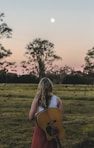 a woman holding a guitar in a field