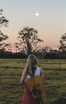 a woman holding a guitar in a field