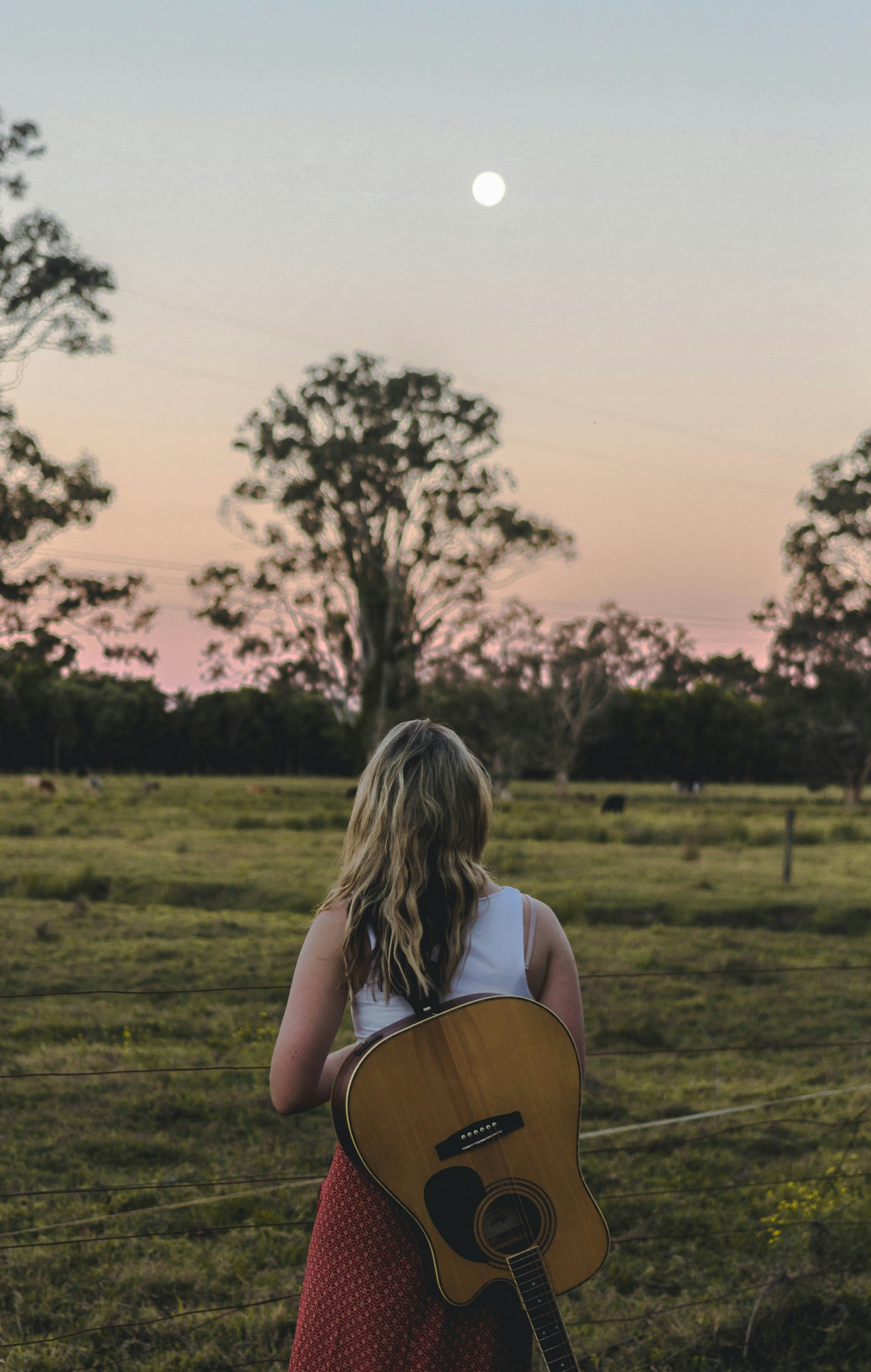 a woman holding a guitar in a field
