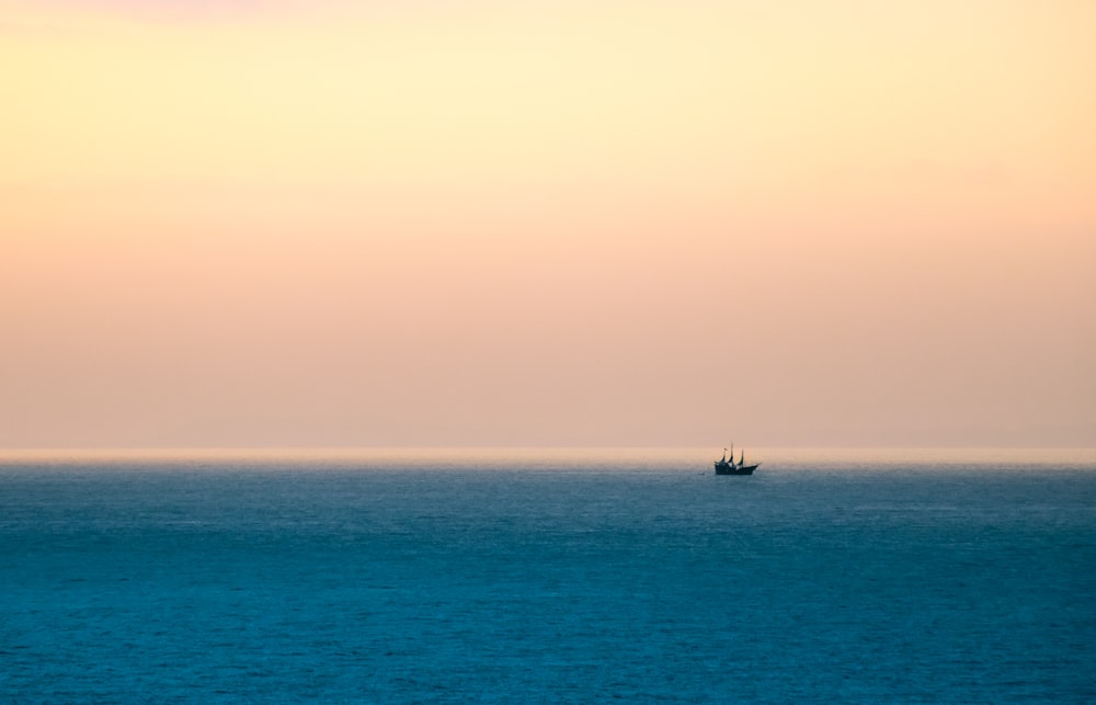 Silhouette eines Bootes, das tagsüber unter bewölktem Himmel segelt