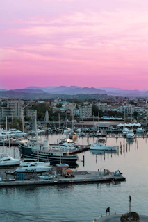 A serene marina at sunset with luxury yachts docked under a colorful sky.