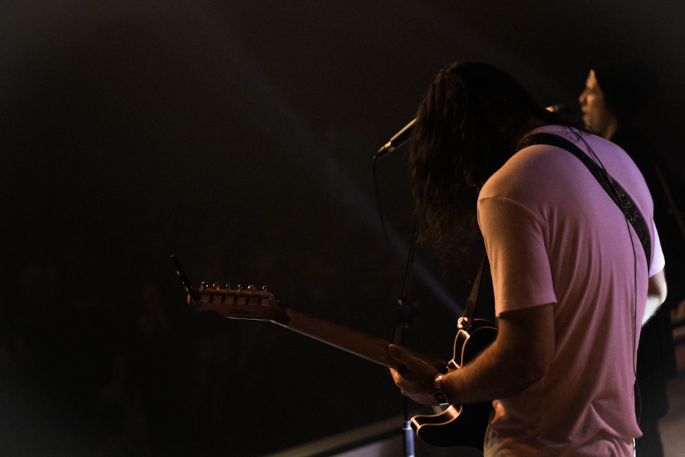 man standing while playing guitar