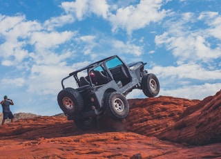 gray 4x4 vehicle climbing the rock during daytime