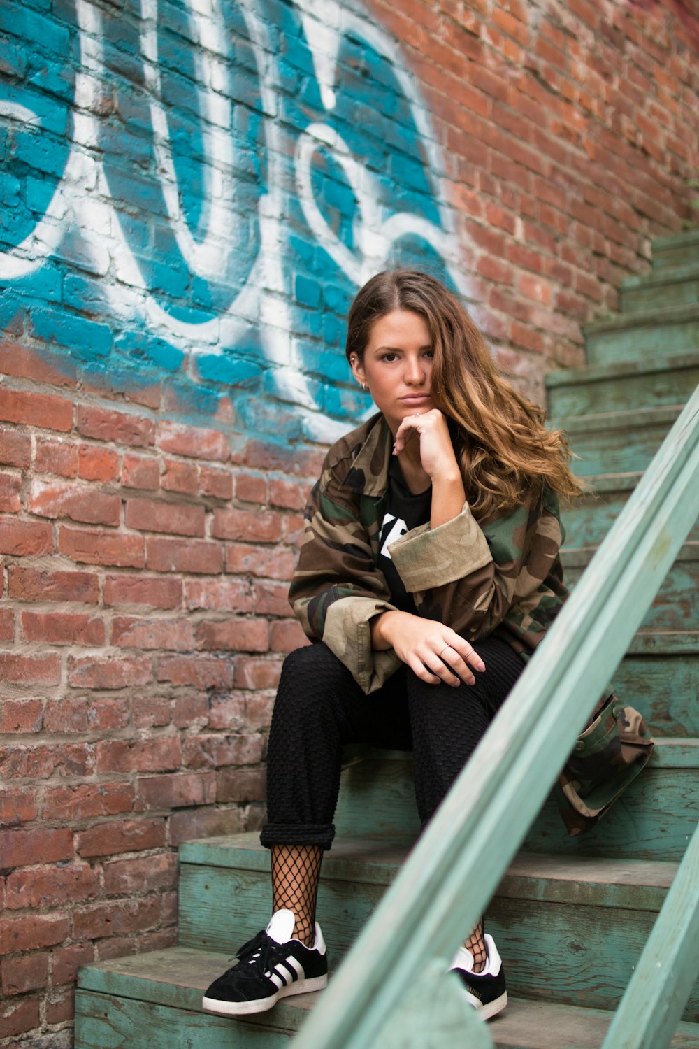 woman sitting on staircase near wall