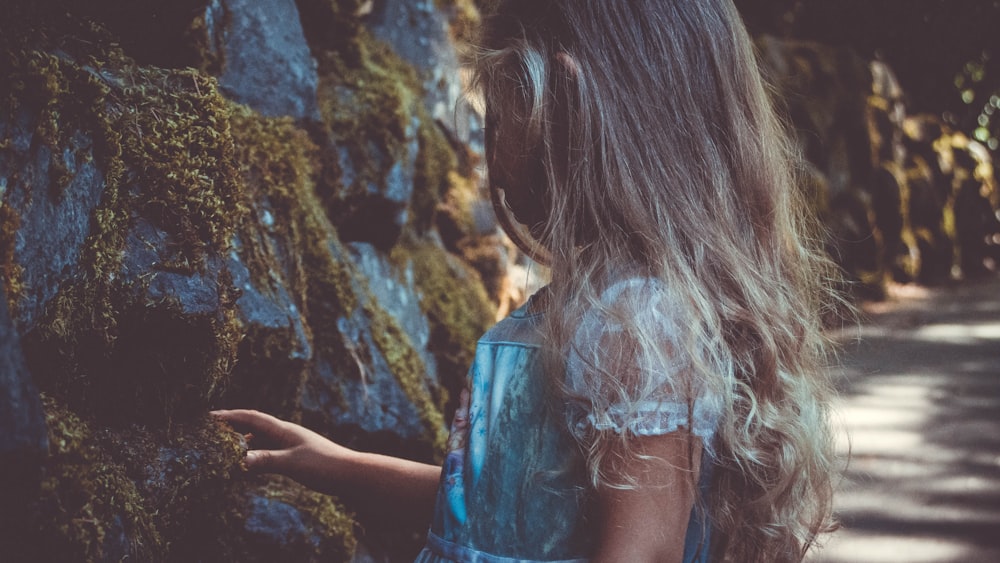 girl wearing lace dress standing near rocks